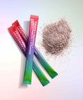 Three colorful packets of Juice Plus+ Superfood sachets on a light background with a pile of powder.