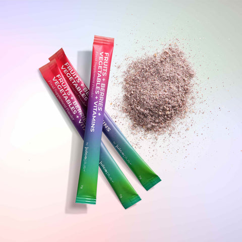 Three colorful packets of Juice Plus+ Superfood sachets on a light background with a pile of powder.